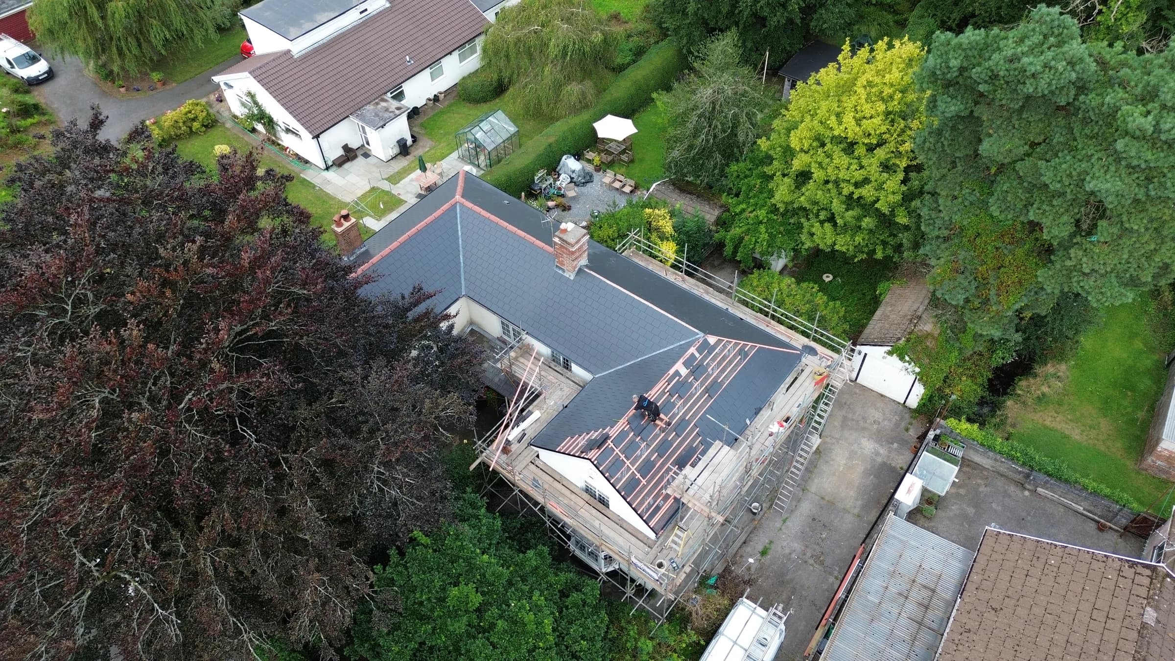 Slate roof replacement in progress, old and new side by side, aerial view, Neath