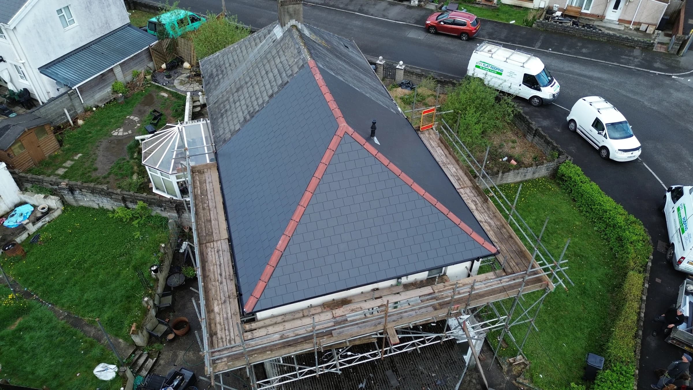 New grey slate hipped roof with red ridge tiles, completed in Neath