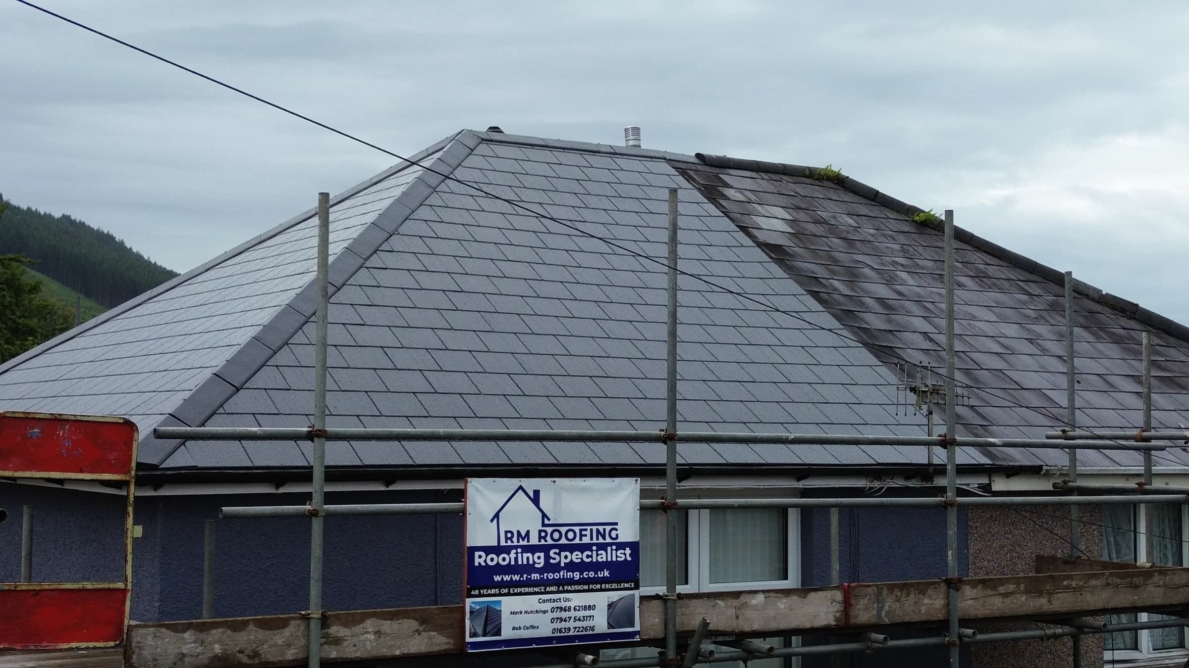 RM Roofing banner on scaffolding in front of a completed roof in Neath